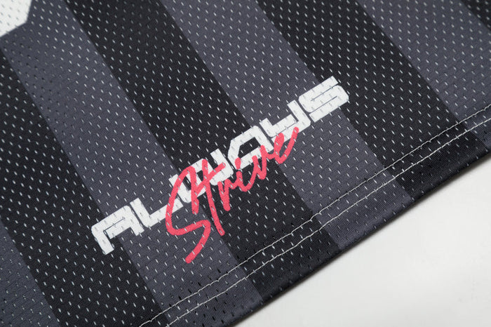 Close-up of black mesh football jersey with grey vertical stripes and red-white graphic logo near the hem