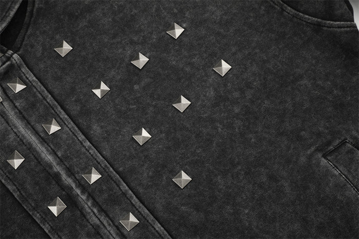 Close-up of pyramid studs across the acid-washed black hoodie chest beside the front pocket