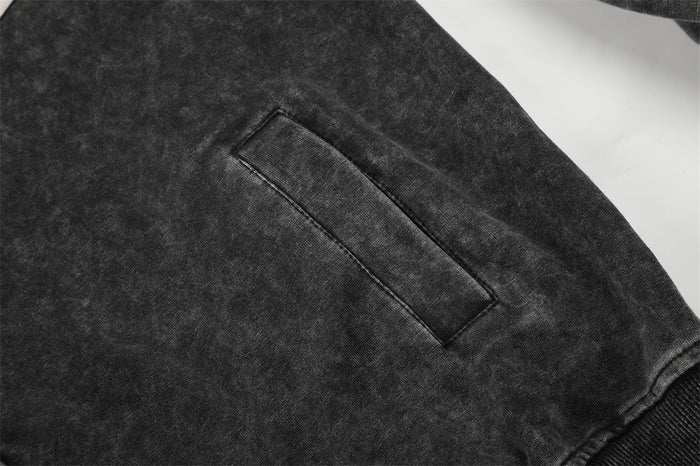 Close-up of the acid-washed black hoodie showing a stitched welt pocket on the sleeve or side panel