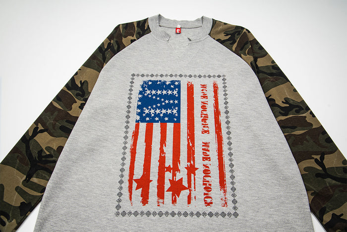 Close front view of gray waffle-knit raglan shirt with camouflage sleeves and American flag graphic