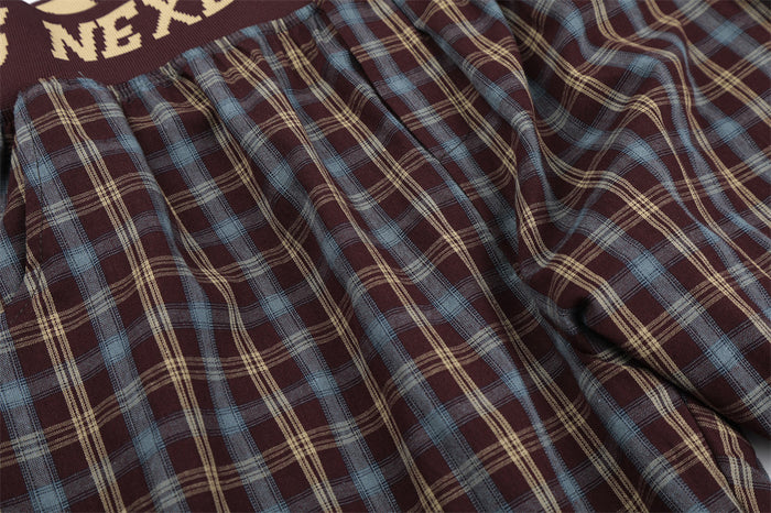 Close-up of burgundy plaid fabric with blue and beige checks and gathered waist seam