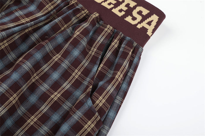Close-up of plaid pants waistband and side seam with burgundy knit elastic band