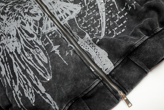 Close-up of the dark hoodie lower front showing printed artwork, metal zipper, and ribbed hem