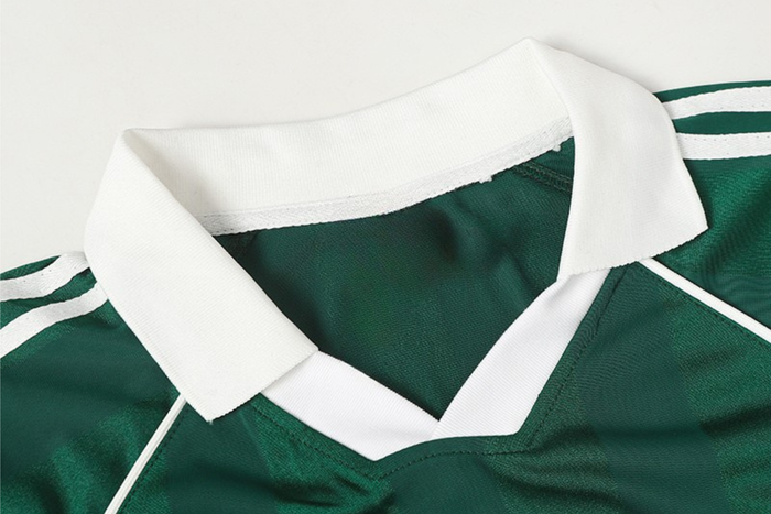 Green performance soccer jersey with white collar and sleeve stripes, shown in a close-up streetwear style fit