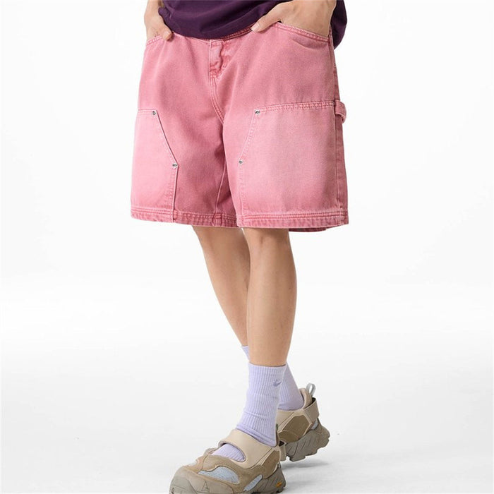 Pink denim carpenter shorts shown from a front-right angle with utility pockets and side loop