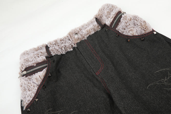 Close-up of the jeans front showing the plush beige waistband, zipper pocket, red stitching, and metal studs