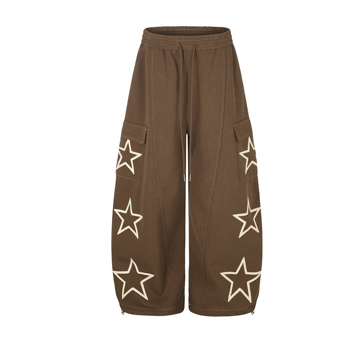 Baggy wide-leg cargo sweatpants with oversized star appliqués in brown, featuring flap cargo pockets and ankle zip closures