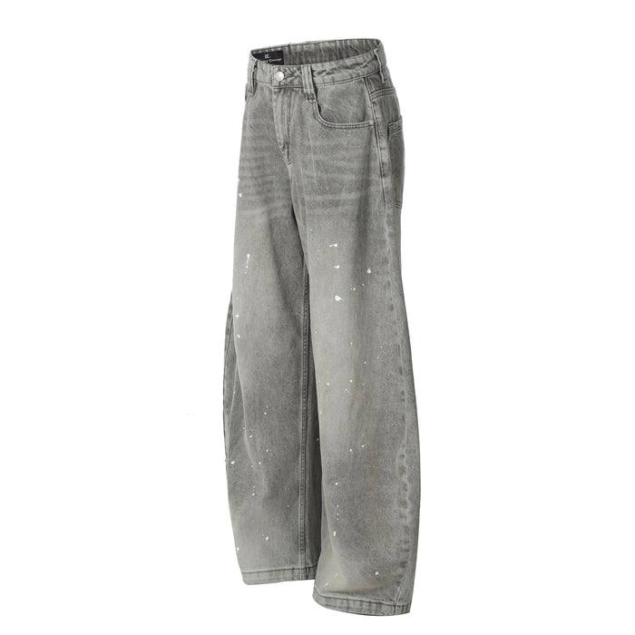 Angled front view of grey wide-leg jeans with acid-washed shading and scattered white paint splatters
