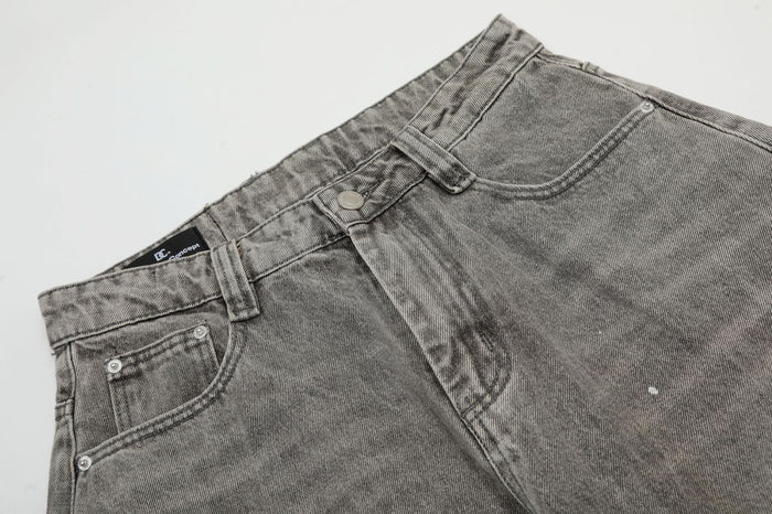 Close-up of the grey denim jeans front showing belt loops, button closure, curved pockets and acid-washed texture