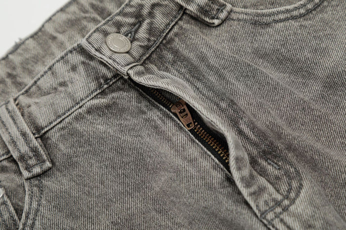 Close-up of the jeans front showing the metal button, belt loop and partially opened zip fly