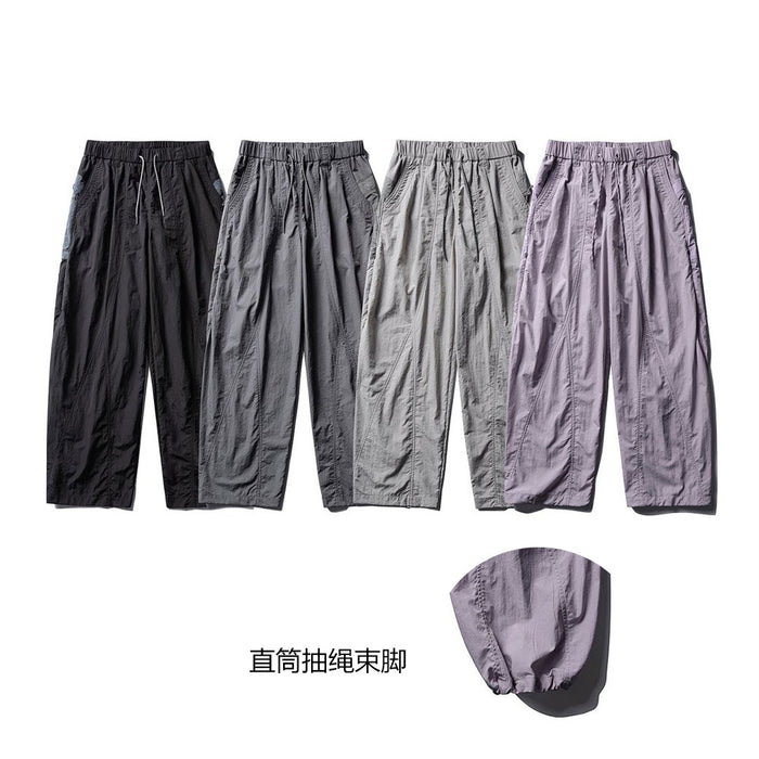 Four pairs of wide-leg parachute pants in black, charcoal, gray, and lavender with elastic cuffs