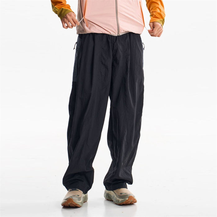 Black wide-leg parachute pants shown from the front on a standing model with gathered ankle cuffs