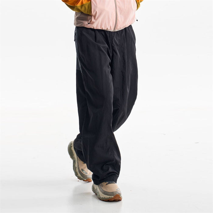 Black wide-leg pants shown in a front walking view with elastic waist and gathered cuffs