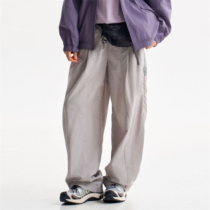 Light gray wide-leg parachute pants shown from the front on a model with a drawstring waist