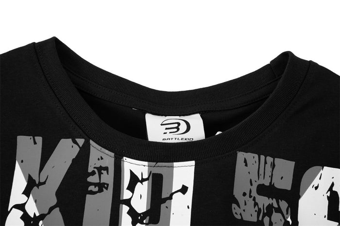 Black oversized graphic T-shirt with bold distressed lettering and ribbed crew neckline, close-up of chest and collar