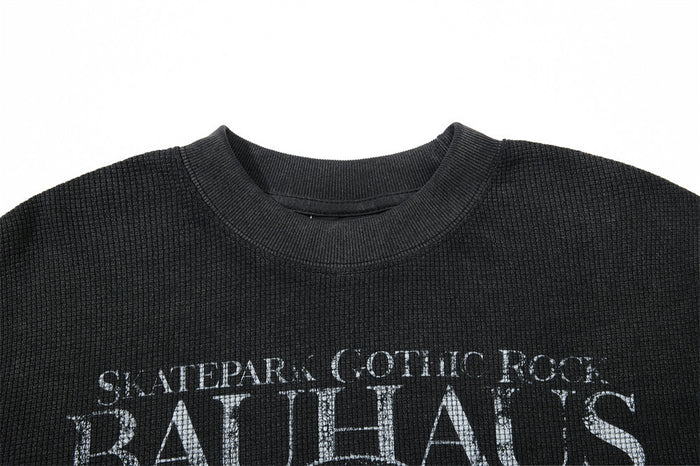 Close-up of the ribbed crew neckline and distressed Bauhaus Gothic Rock text on a black shirt