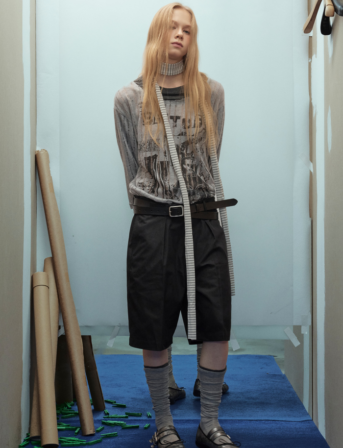 Model front view of gray graphic sweater with striped sleeves, layered with long striped ties