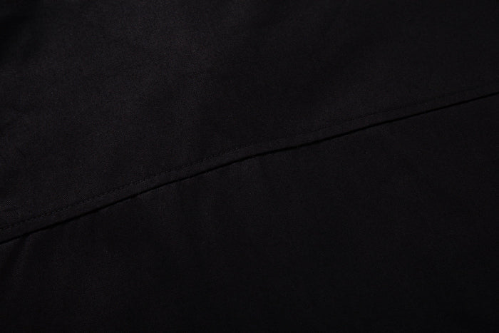 Close-up of black fabric with diagonal seam detail on a Seakoff graphic button-up streetwear shirt