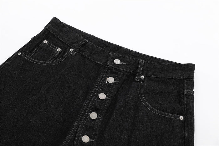 Close-up of black denim shorts front waist with diagonal button placket