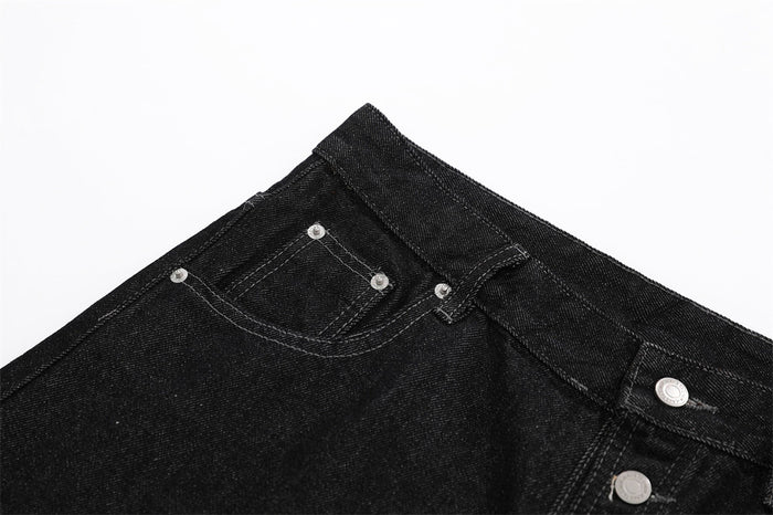 Angled close-up of black denim shorts waistband and front button placket