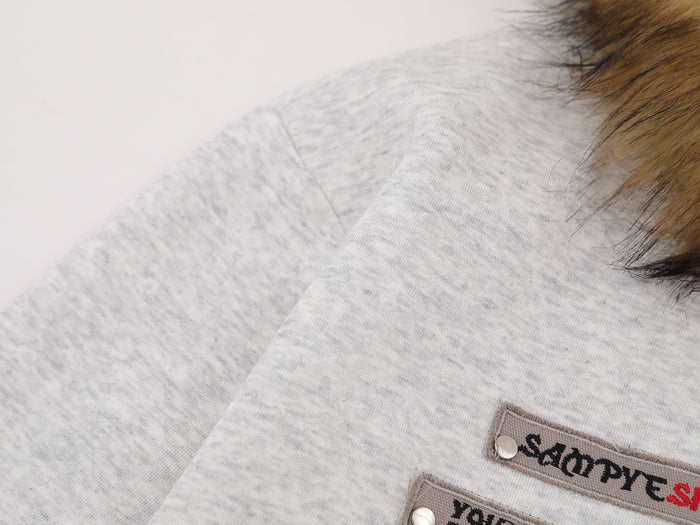 Close-up of light gray hoodie sleeve and printed chest patch detail