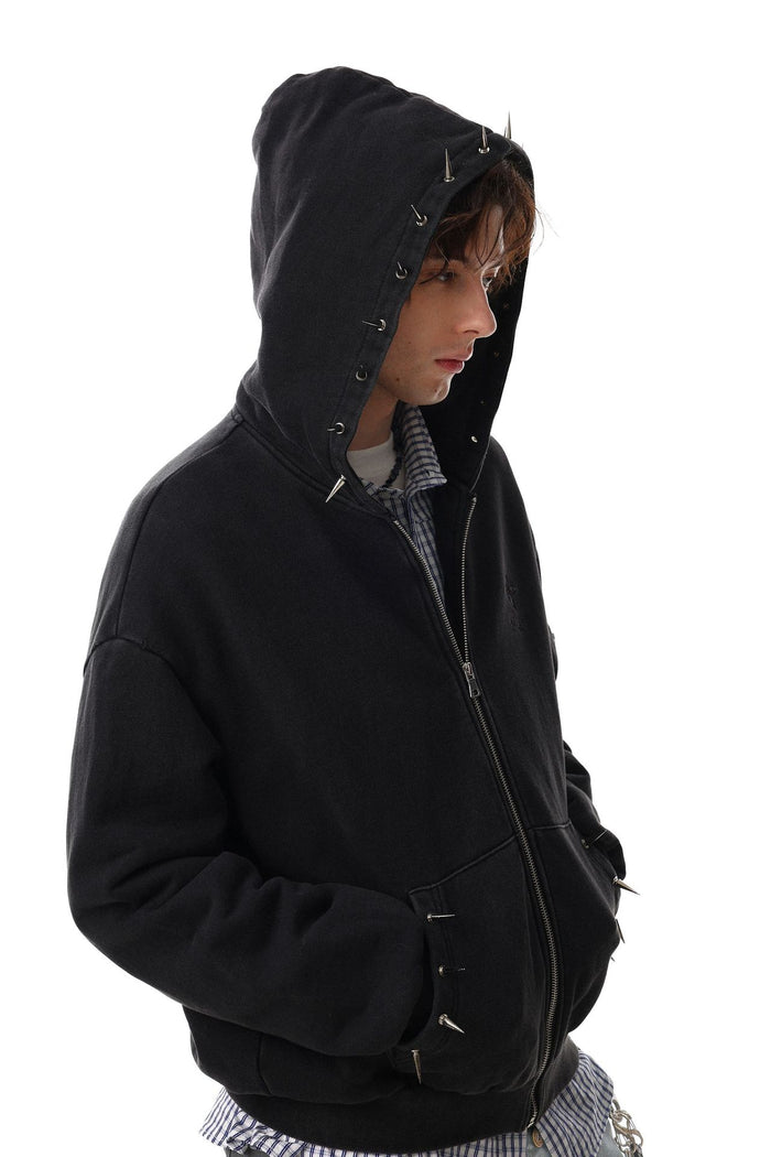 Side view of a black zip-up hoodie with raised hood, metal spikes, and a washed finish