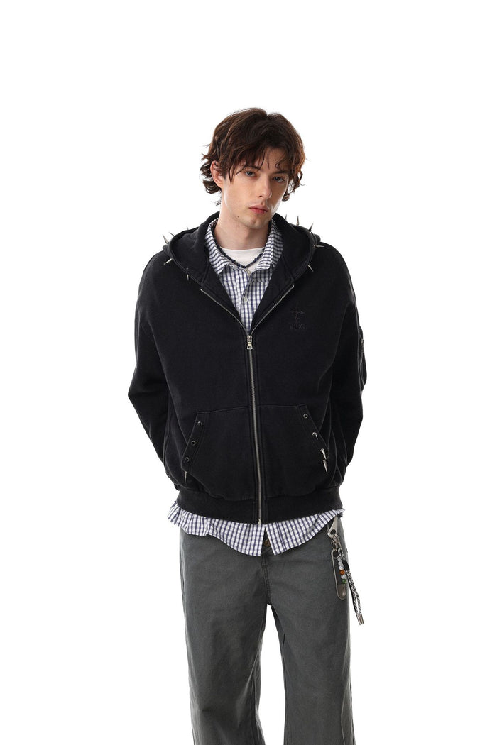 Model wearing a black zip-up hoodie with hood resting behind the neck and front pockets
