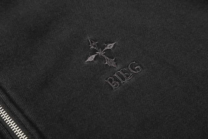 Close-up of subtle embroidered lettering and a small emblem on the black hoodie chest