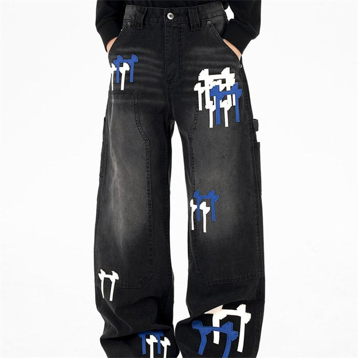 Front view of black washed wide-leg cargo jeans with white and blue cross embroidery patches