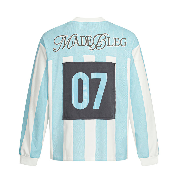 Back view of light blue striped long sleeve tee with MADEBLEG text and black 07 patch graphic