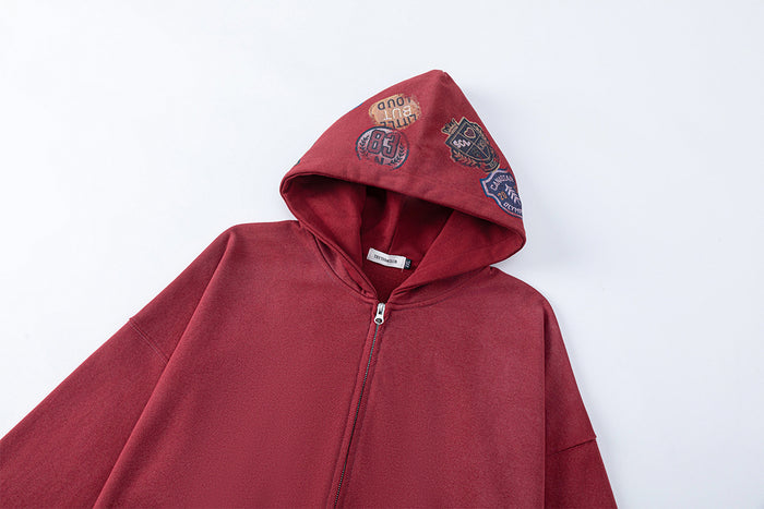 Close-up of the red hoodie showing its open hood, embroidered patches, and front zipper