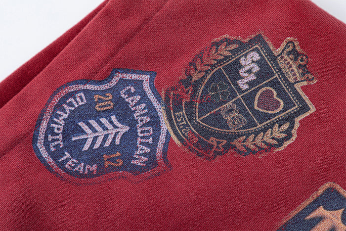 Close-up of embroidered shield-style patches on the red hoodie fabric