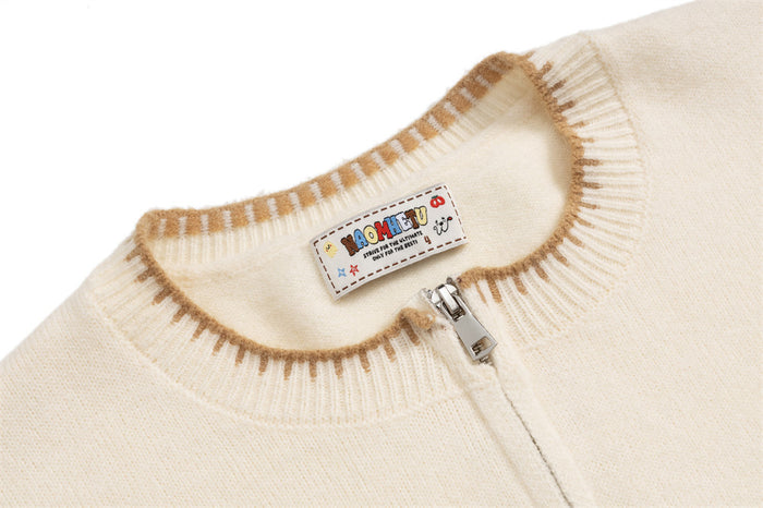Close-up of cream cardigan ribbed collar, metal zipper, and sewn-in neck label