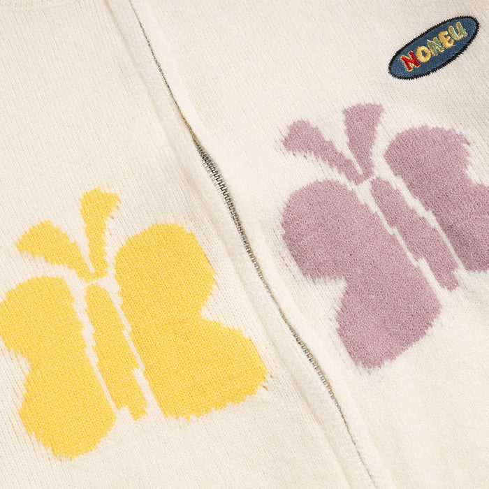 Knit detail of yellow and pink butterfly motifs beside the front zipper and oval embroidered patch