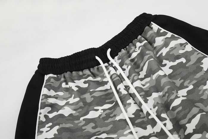 Close-up of the black elastic waistband, white drawstring, gray camouflage fabric, and black side panel