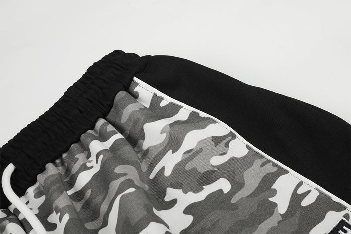 Close-up of the black waistband and side panel with white piping on gray camouflage sweatpants