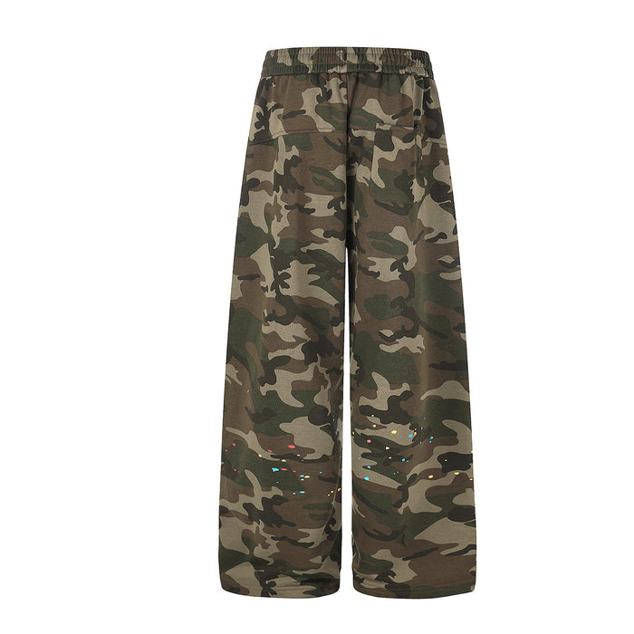 Back view of wide-leg camouflage sweatpants with scattered multicolor paint splatter near the lower legs
