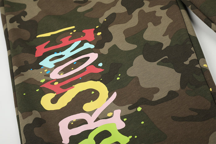 Close-up of colorful graffiti lettering and scattered paint splatters over the camouflage fabric