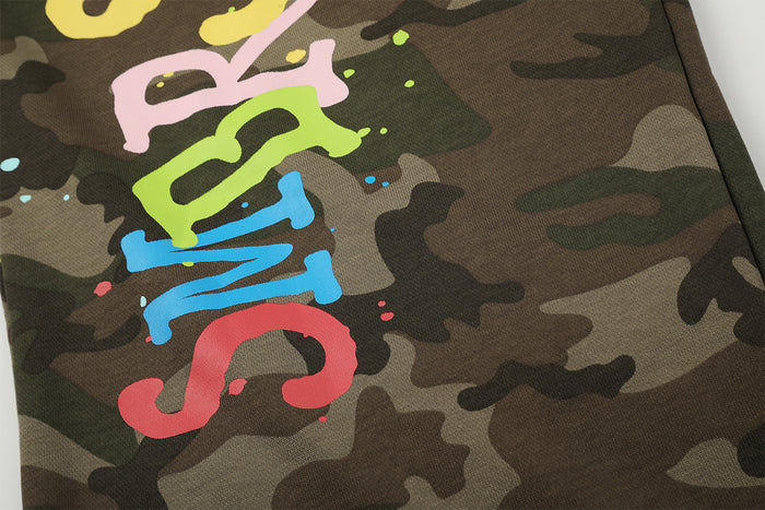 Close-up of multicolor graffiti lettering with small paint splatters on camouflage fabric