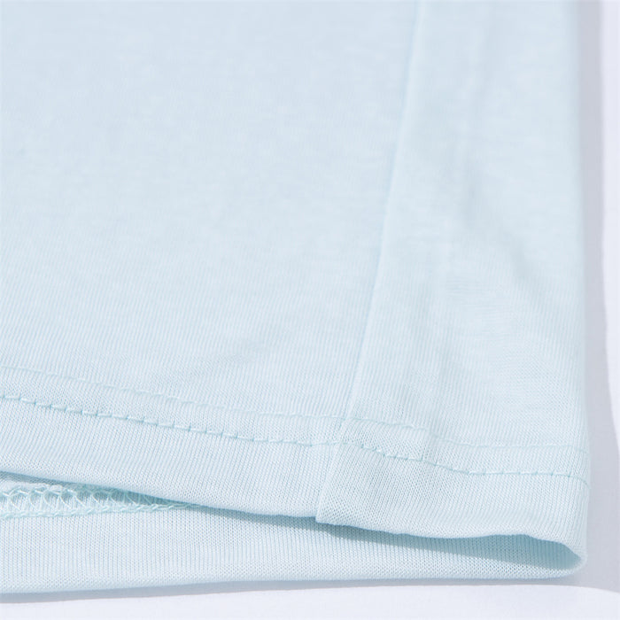 Close-up of the light blue shirt’s stitched bottom hem and smooth lightweight fabric