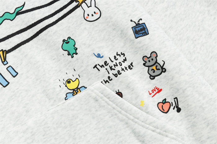 Close-up of the gray hoodie pocket area with cartoon doodles, handwritten text, and colorful accents