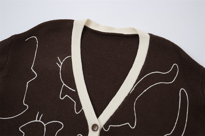 Close-up of the brown cardigan’s cream V-neck trim, knit texture, white cat outline, and shoulder seam