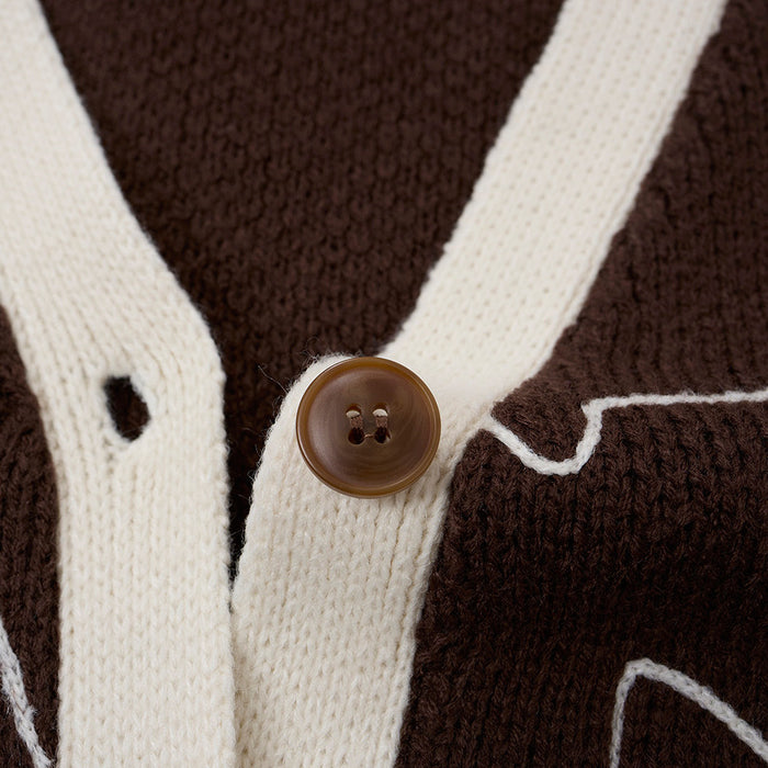 Close-up of a brown four-hole button on cream knit trim with the cardigan’s textured cat-outline fabric