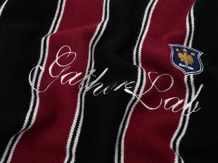 Close-up of burgundy striped knit sweater with script print and crest patch