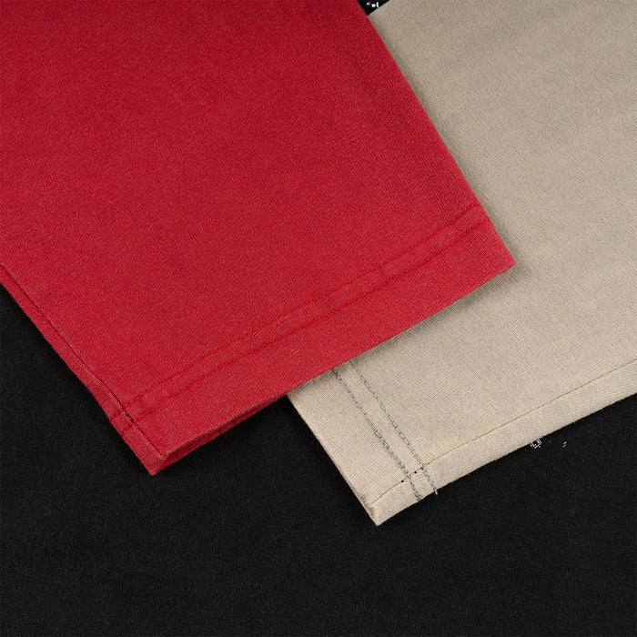 Close-up of red and beige sleeve panels showing fine fabric texture and double-stitched hems over black fabric