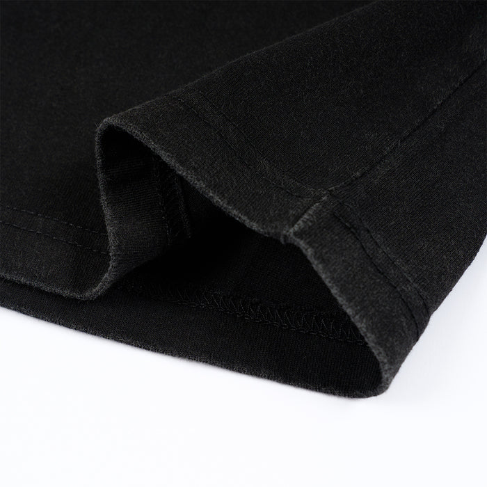 Close-up of the black shirt hem showing folded edges, seam stitching, and overlock stitching detail