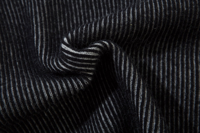 Close-up of folded black ribbed knit sleeve cuff with gray stripes