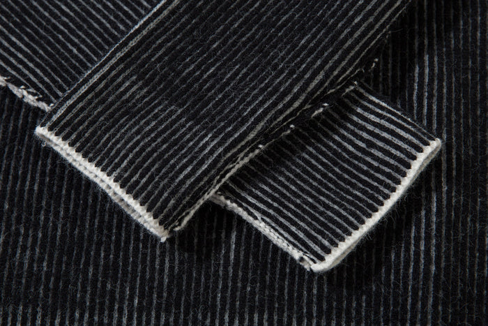 Close-up of folded ribbed sleeve cuff on black striped knit sweater