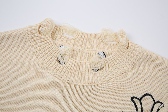 Close-up of cream knit sweater collar with ribbed trim and distressed holes around the crewneck
