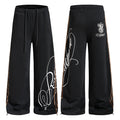 Black wide-leg sweatpants with leopard side tape and white cursive script graphic print, front and back view
